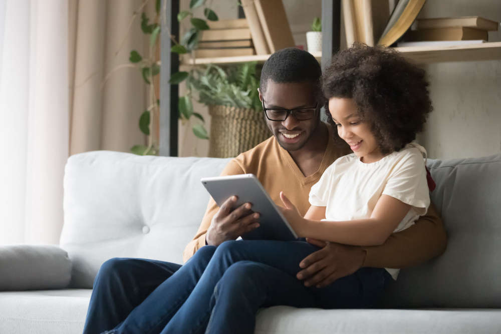 African Father Holds On Lap Daughter Sitting Resting On Sofa